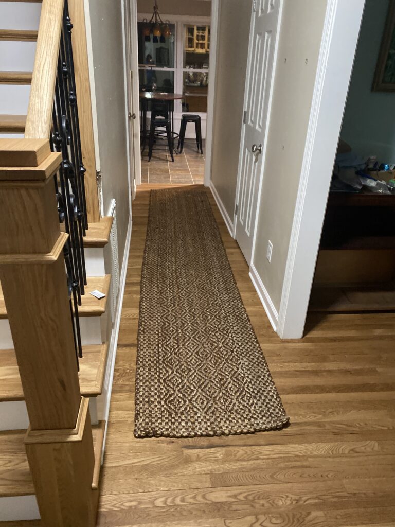 Hallway with patterned rug and wooden stairs.