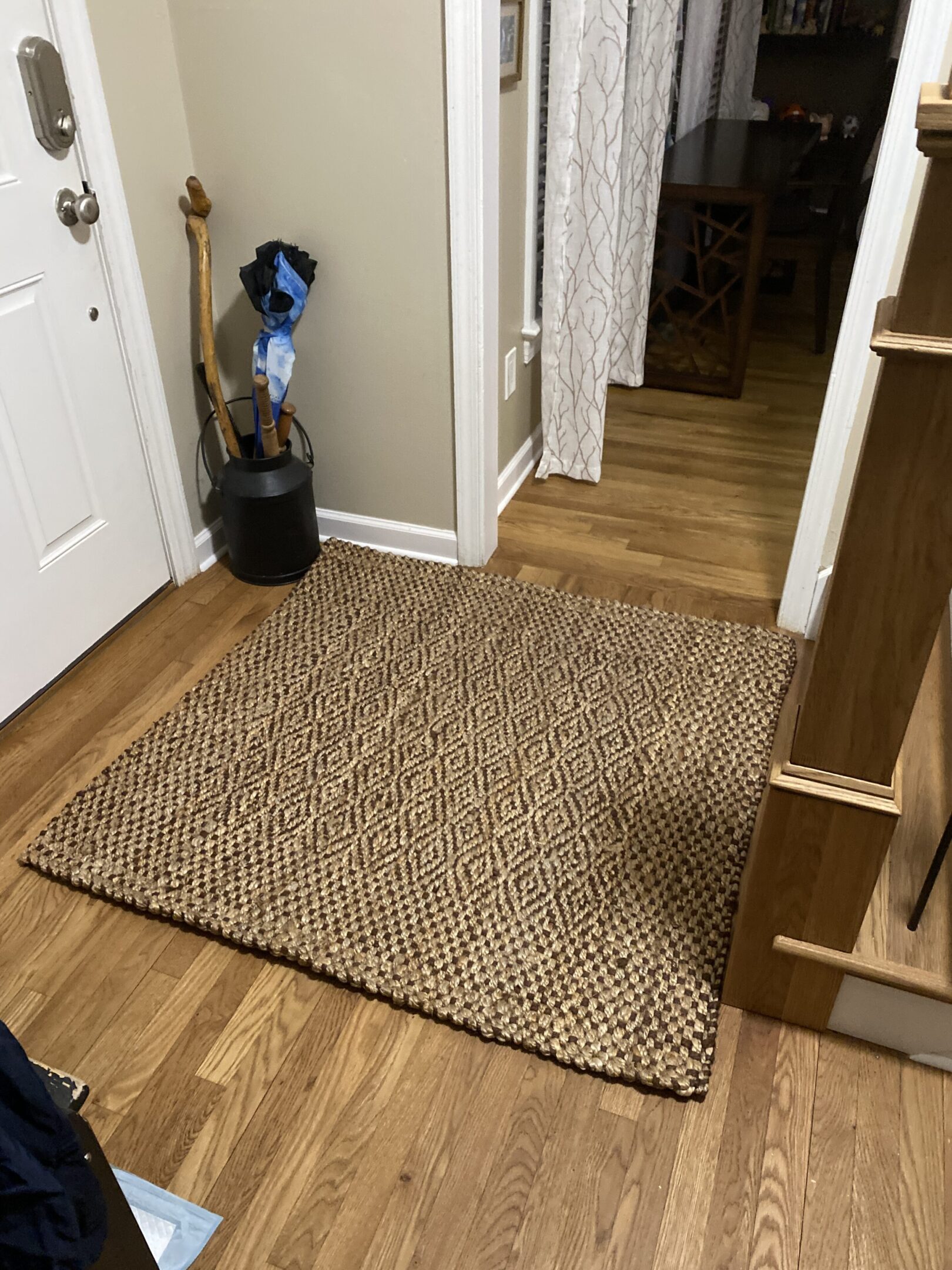 Woven rug and umbrella stand in hallway.