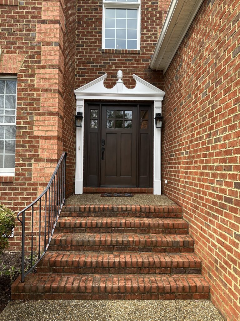 Brick house entrance with brown door.