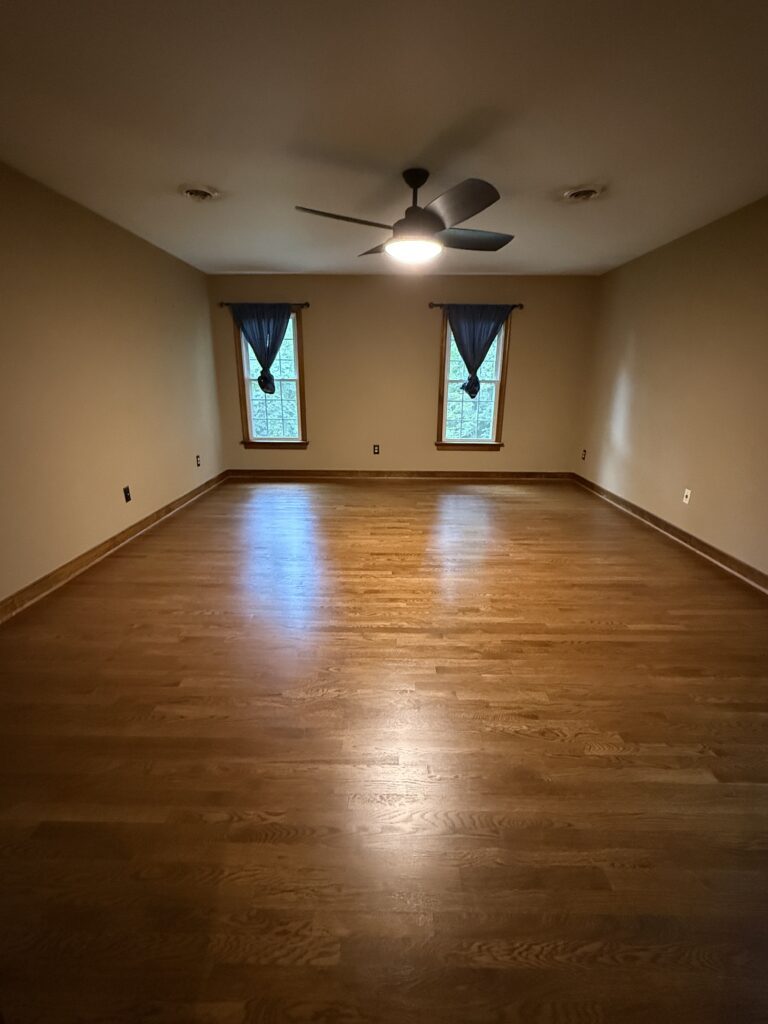 Empty room with wooden floor and windows.