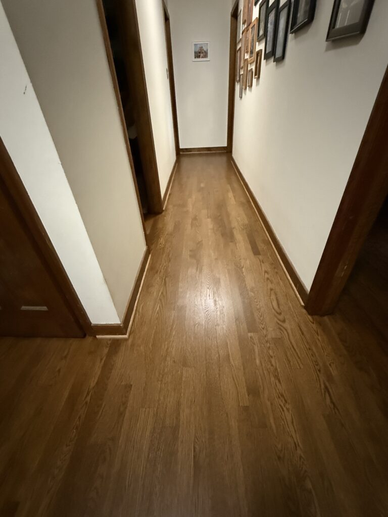 Wooden hallway with framed pictures on walls.