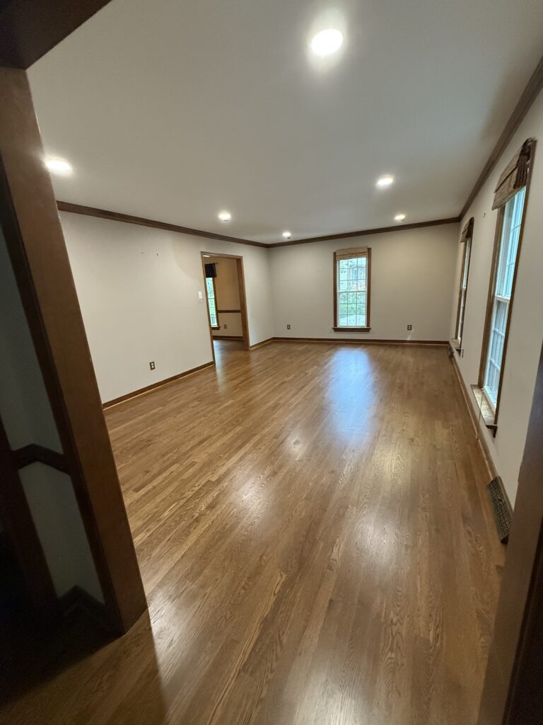 Spacious empty room with wooden flooring.