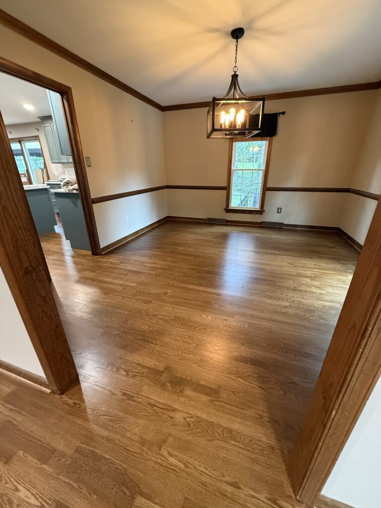 Empty room with wooden floor and chandelier.