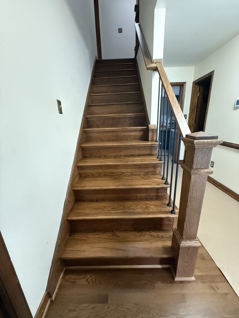 Wooden staircase with railing in hallway.