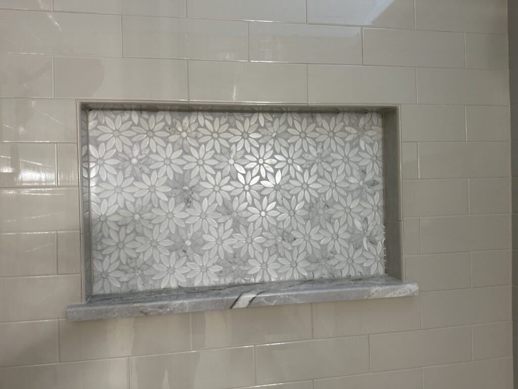 Floral patterned tile niche in shower wall.