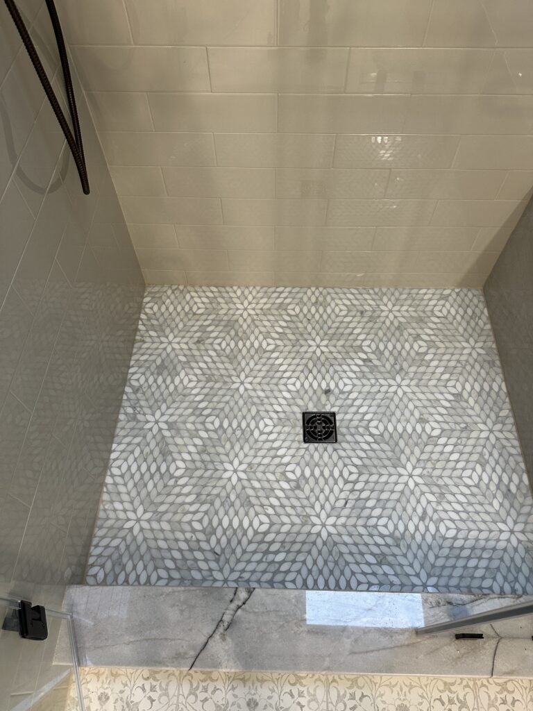 Shower floor with geometric tile pattern.