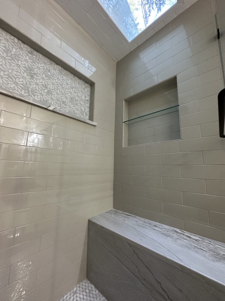 Modern shower with skylight and tiled walls.