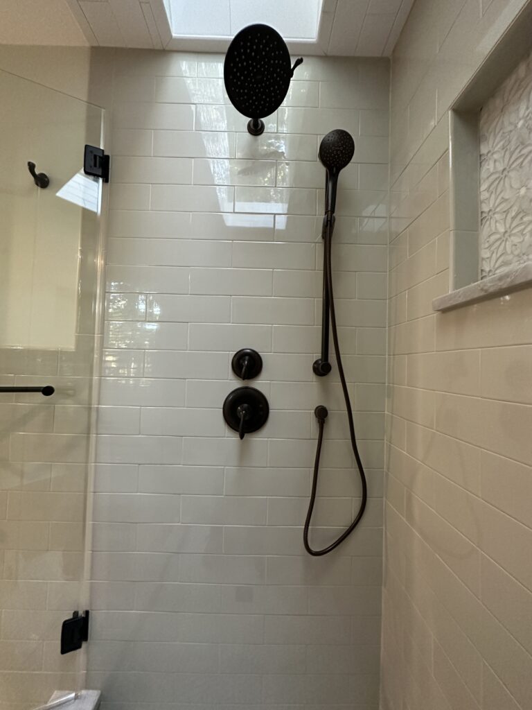 Modern shower with dark fixtures and tiles.