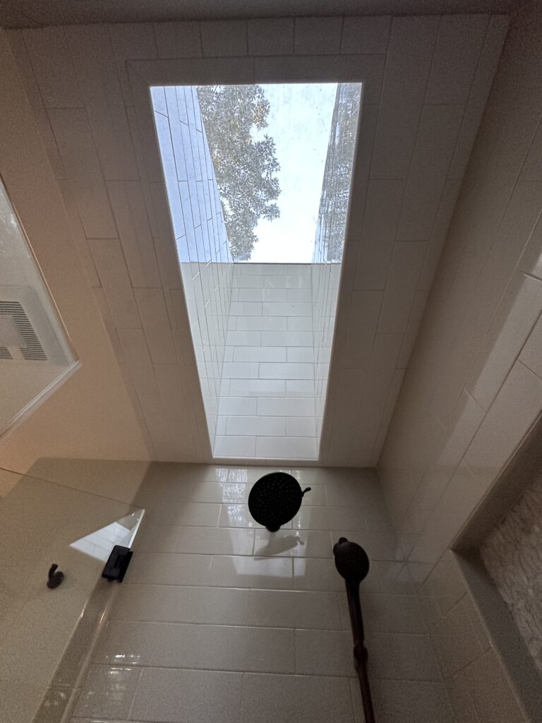 Shower with skylight and white tiles.