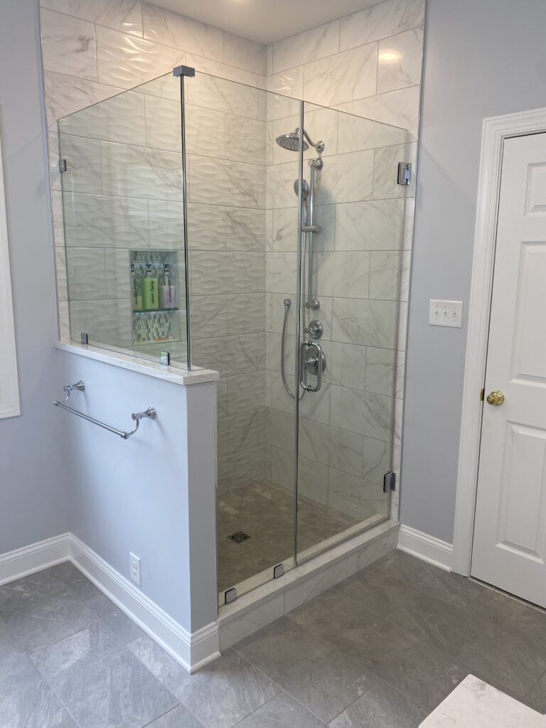 Glass shower enclosure with marble tile walls.