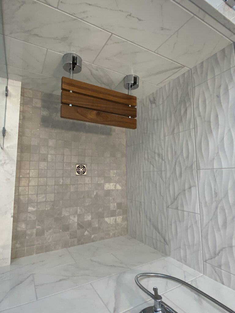 Shower interior with wooden seat and tiles.