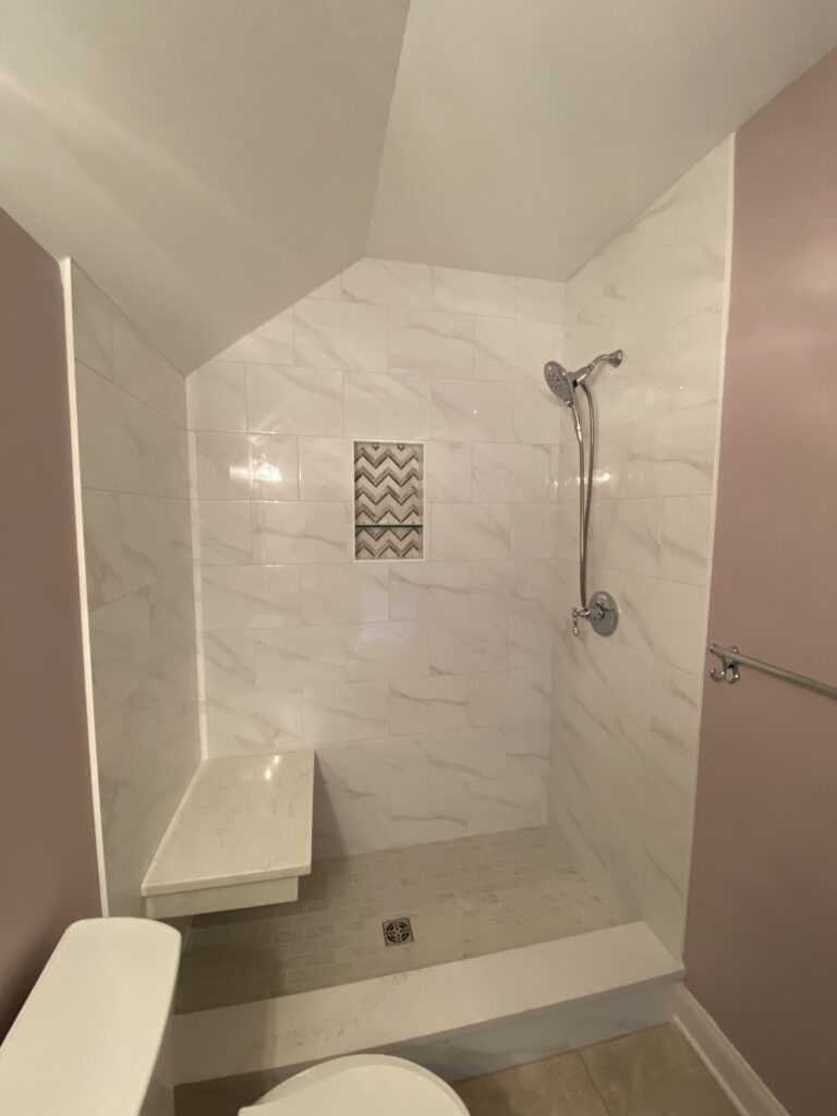 Small bathroom with shower and tiled walls.