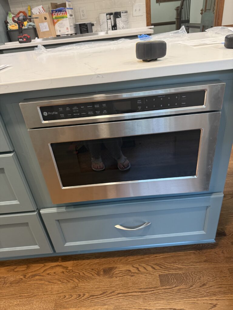 Stainless steel microwave in blue kitchen island.