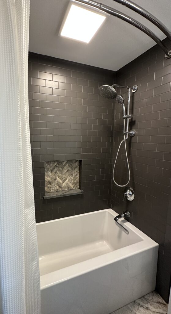 Modern bathroom with dark tiles and bathtub.