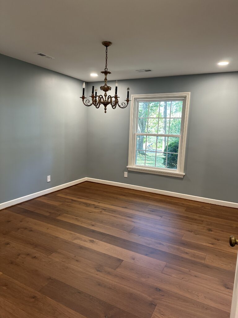 Empty room with chandelier and wooden floor.