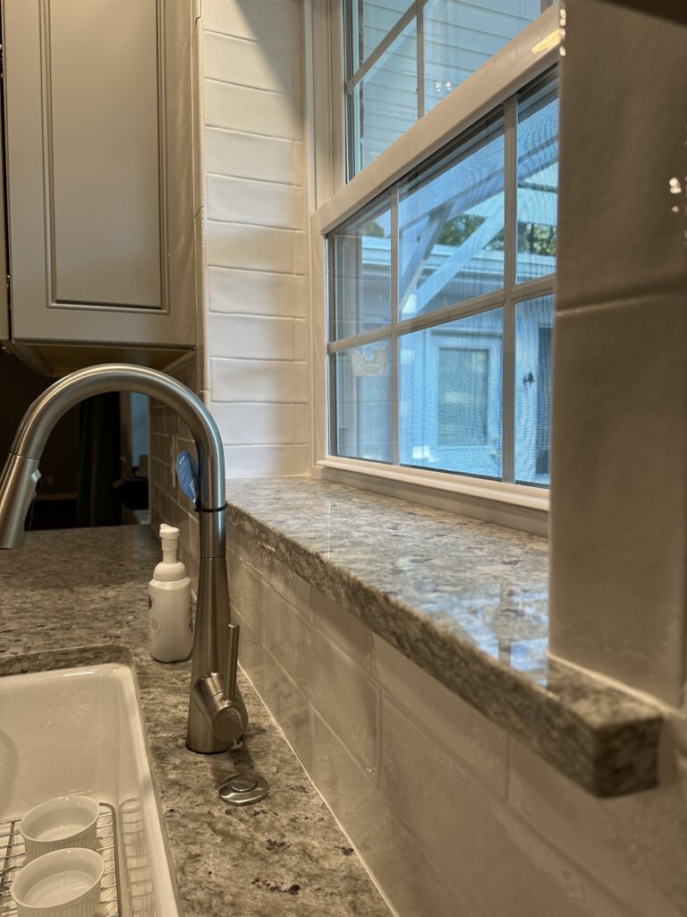 Kitchen sink with granite countertop and window.