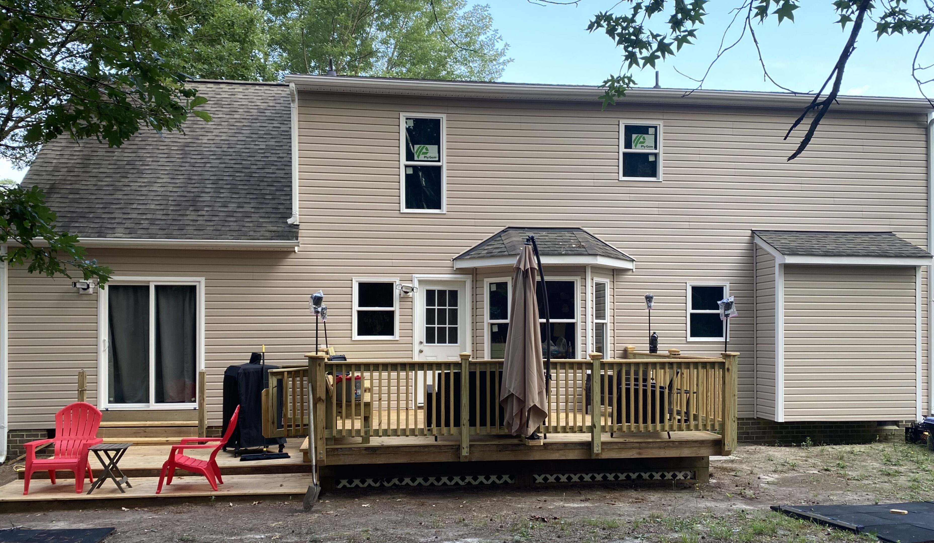 House with wooden deck and red chairs.