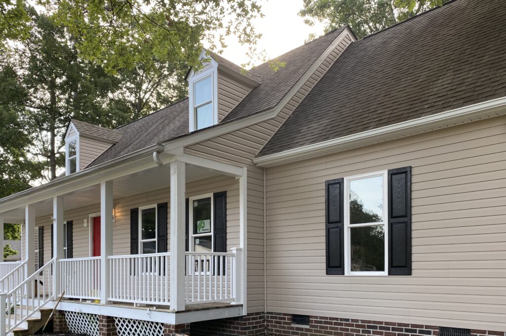 Beige house with porch and dark shutters.