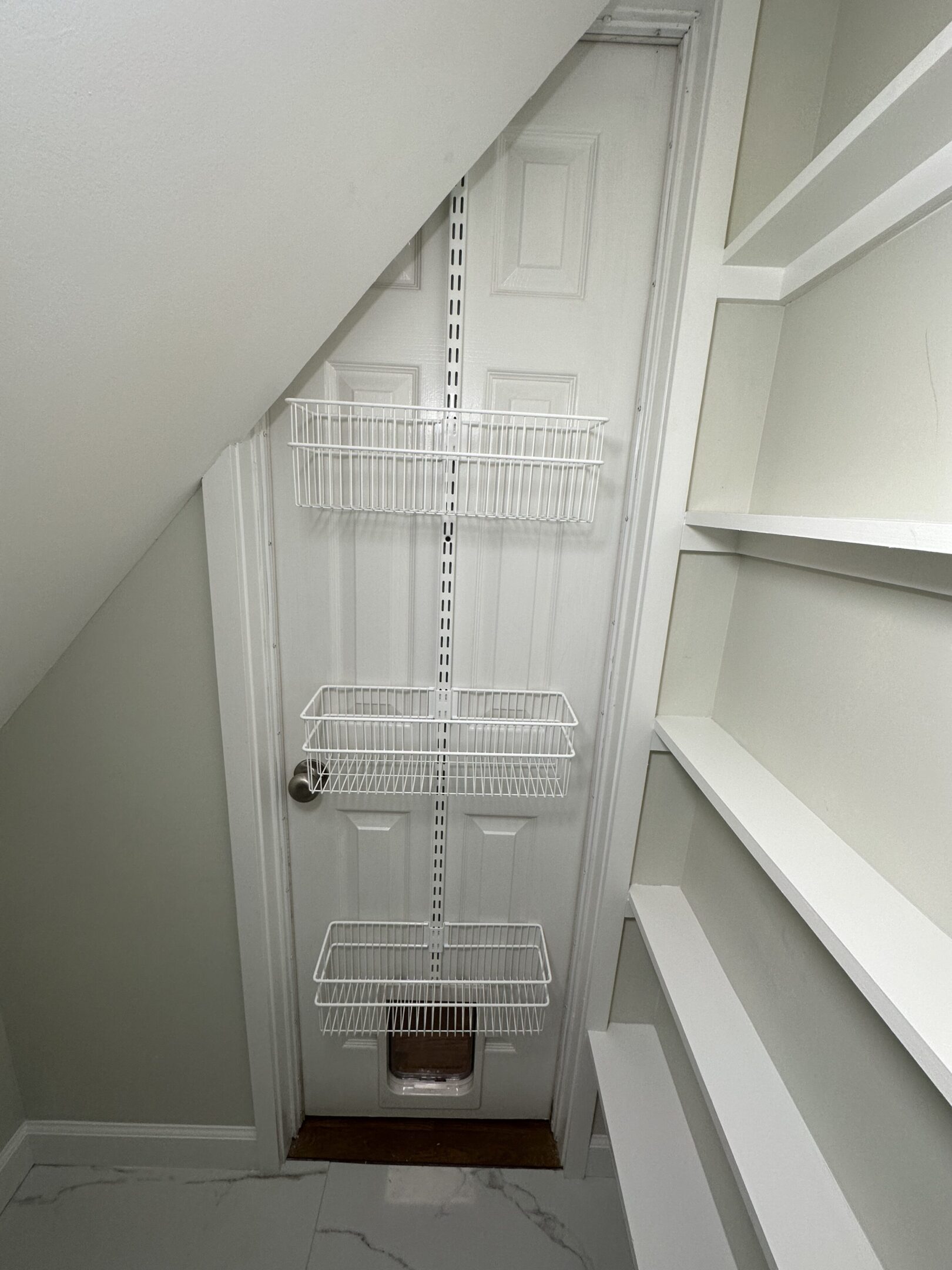 Under-stairs closet with wire shelves.