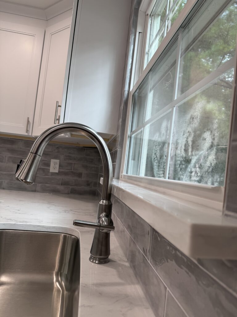 Kitchen sink with modern faucet and window.