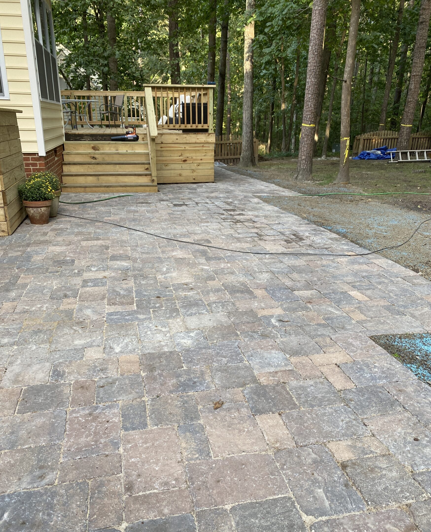 Stone patio with wooden deck in forest.