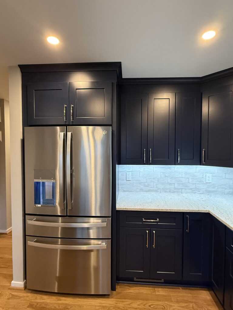 Modern kitchen with dark cabinets and fridge.