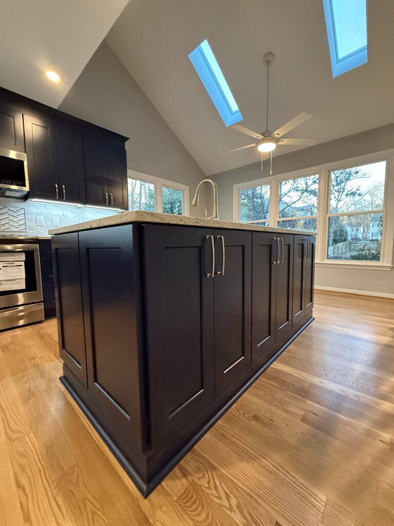 Modern kitchen with dark island and skylights.