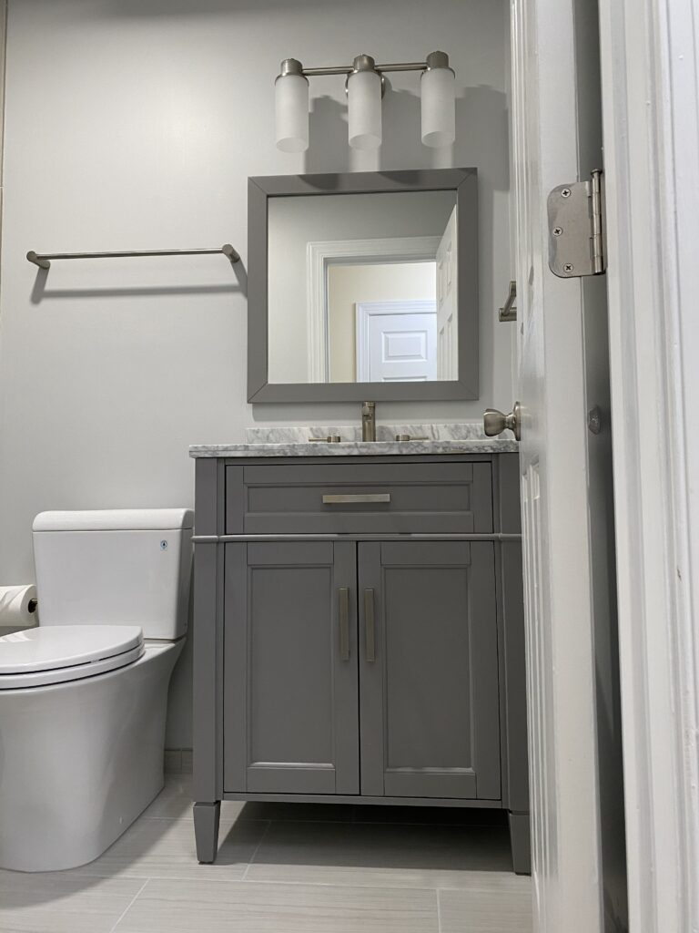 Modern bathroom with gray vanity and mirror.