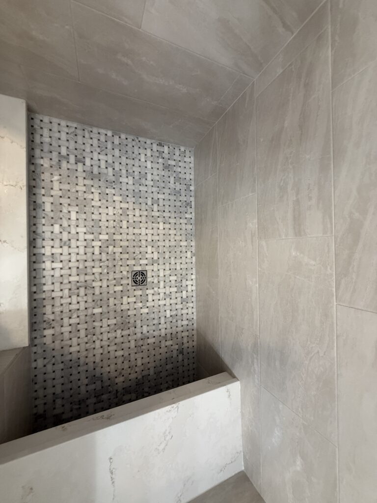 Tiled shower with mosaic accent wall.