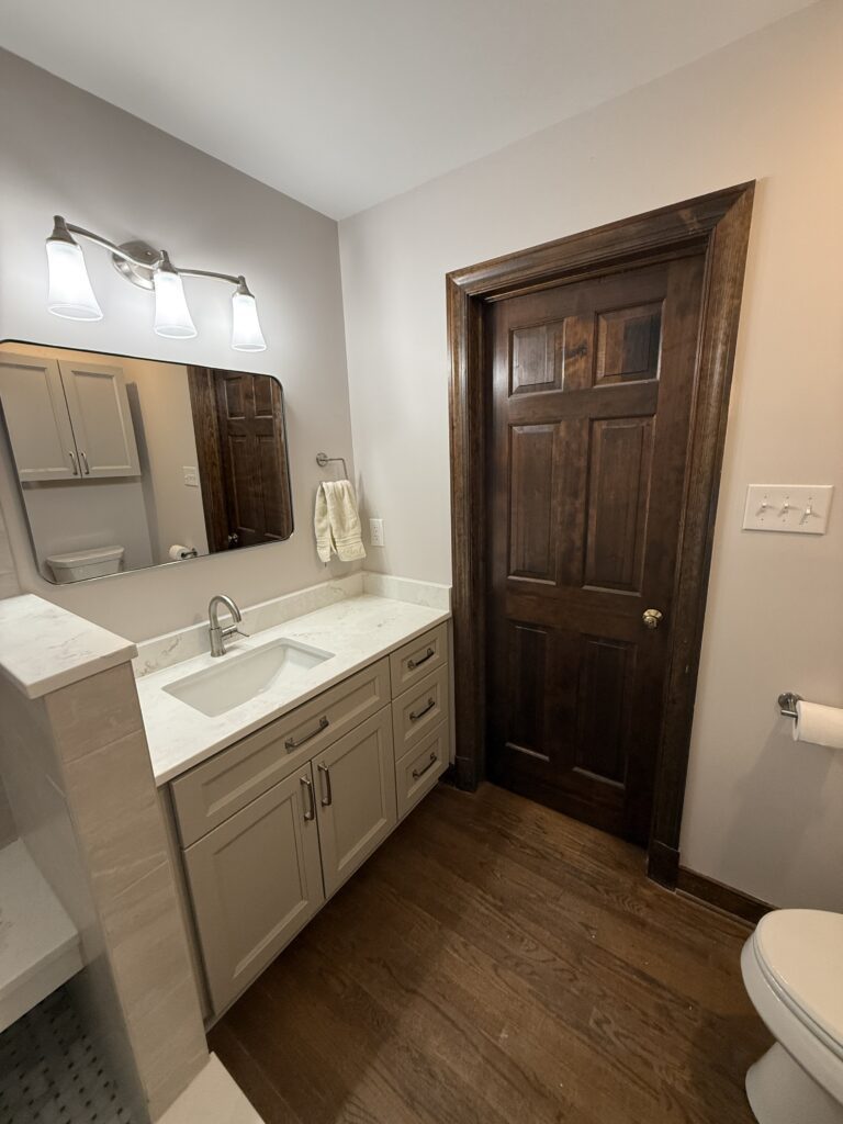 Modern bathroom with wooden door and vanity.