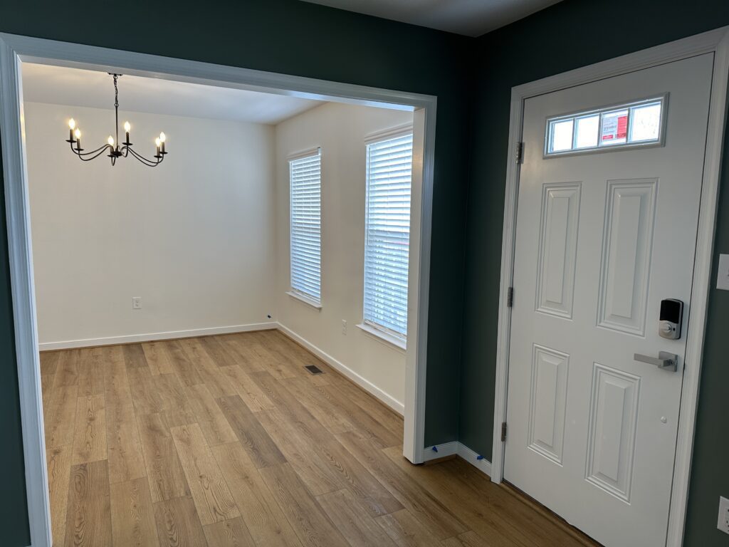 Empty room with chandelier and wooden floor.
