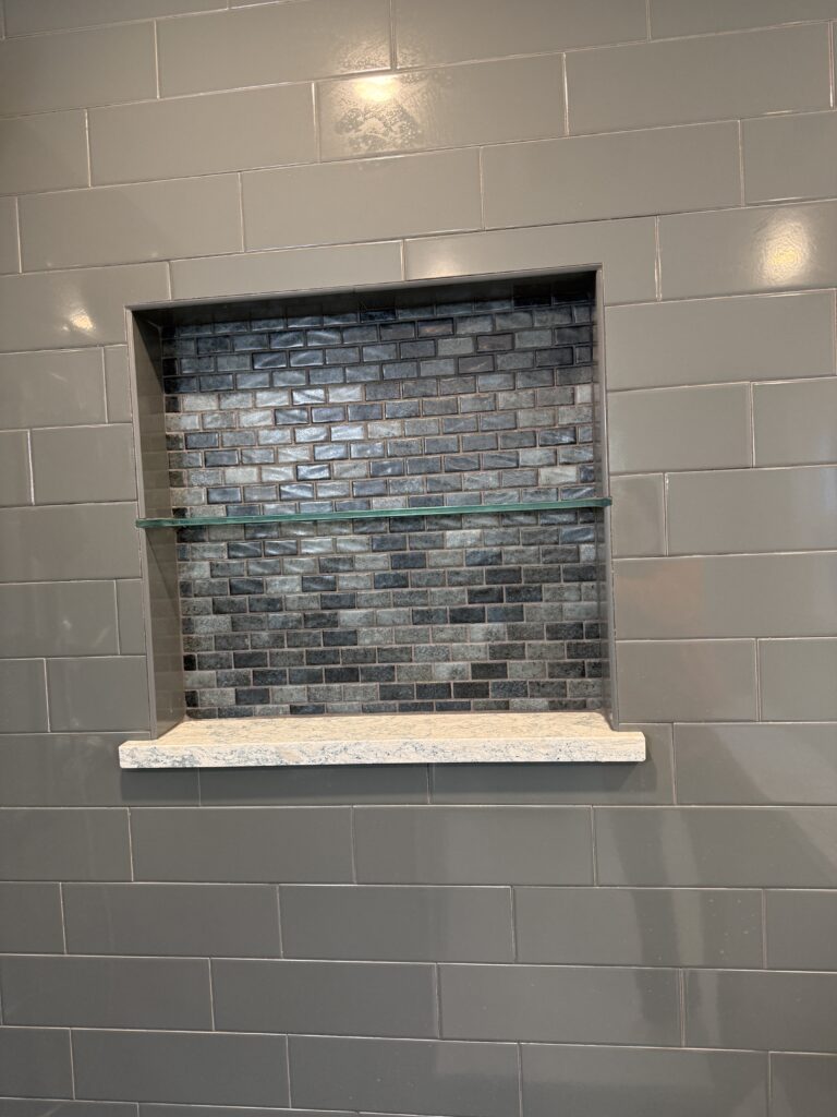 Gray tiled wall with recessed shelf.