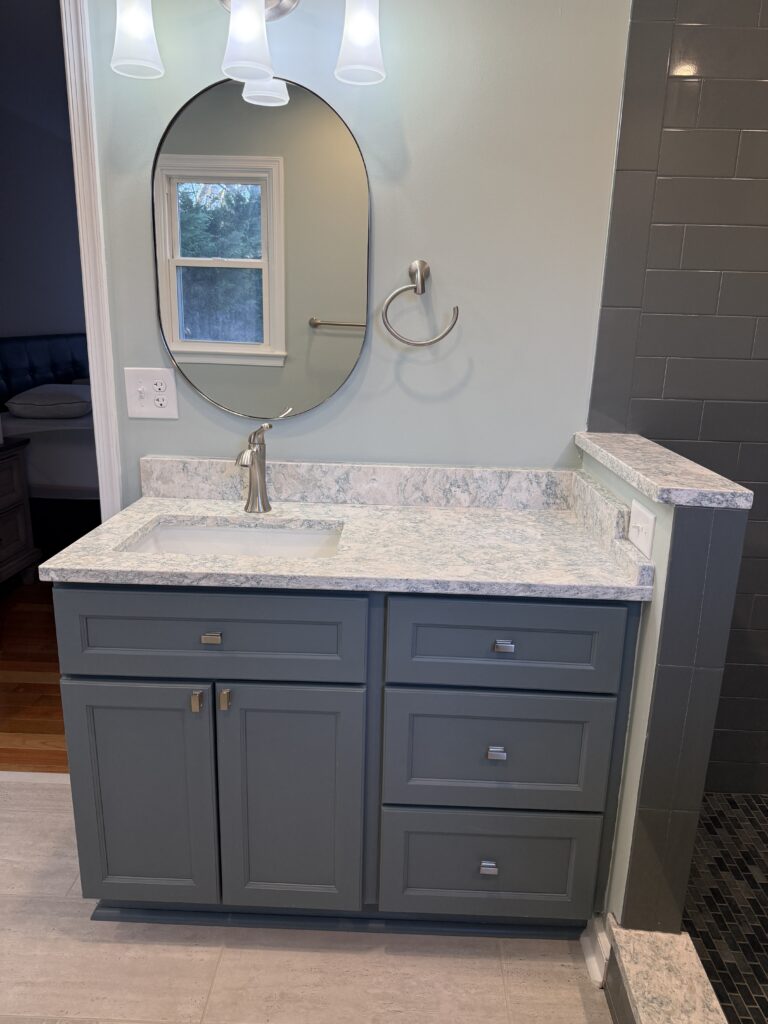 Bathroom vanity with oval mirror and sink.
