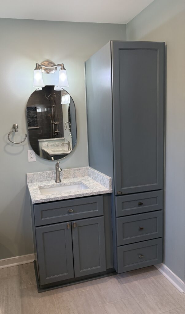 Gray bathroom vanity with oval mirror.