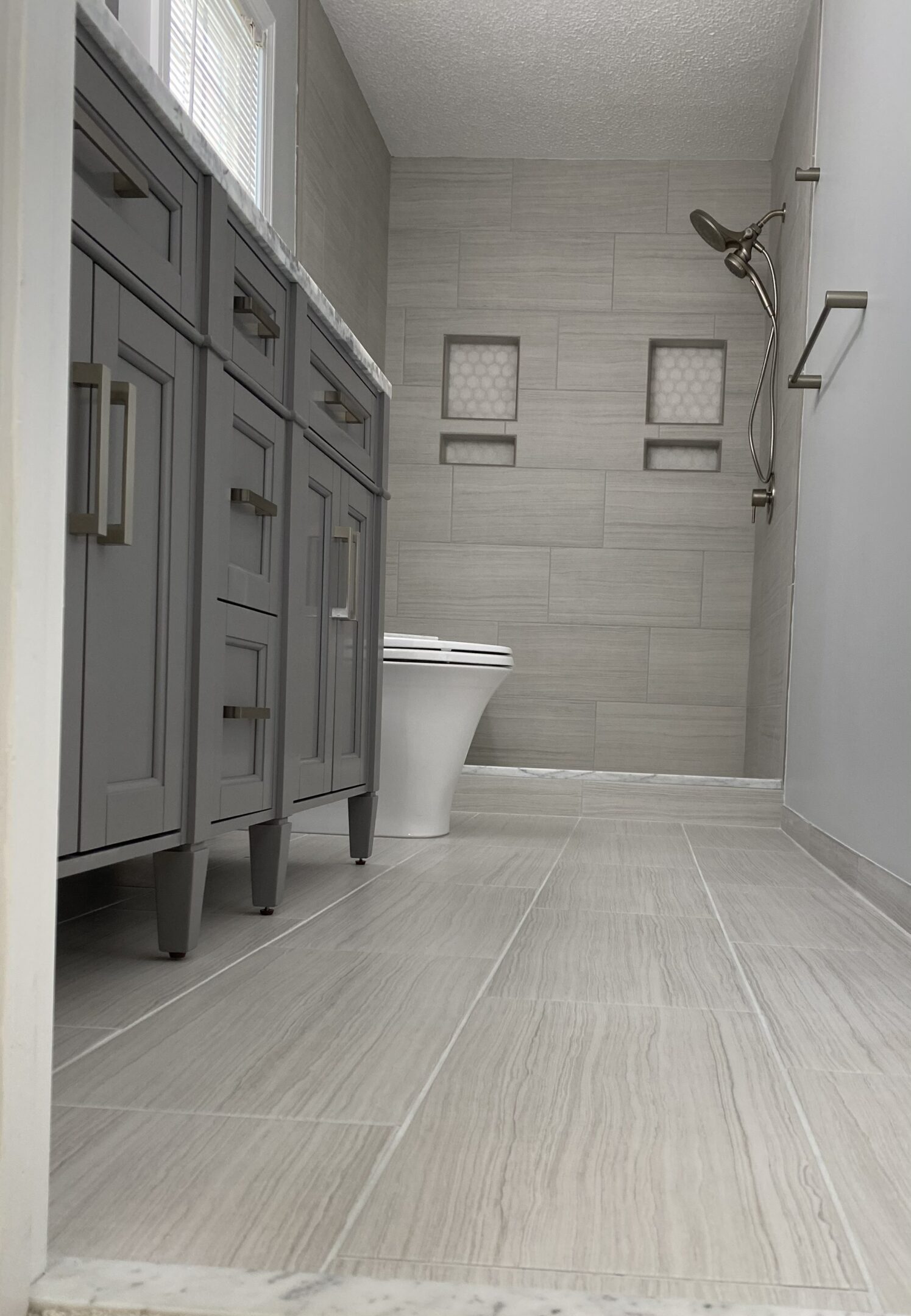 Modern bathroom with gray tiles and cabinets.