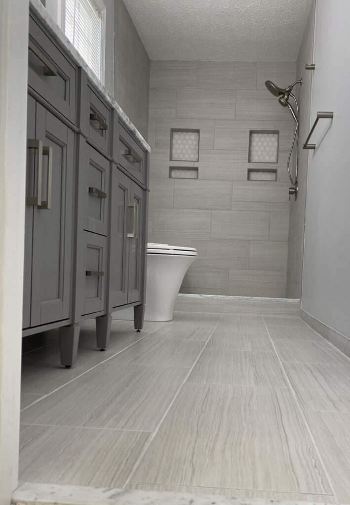 Modern bathroom with gray cabinets and tiles.