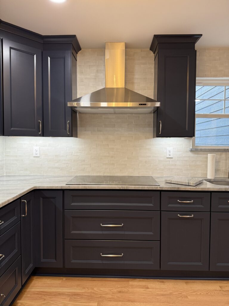 Modern kitchen with dark cabinets and hood.
