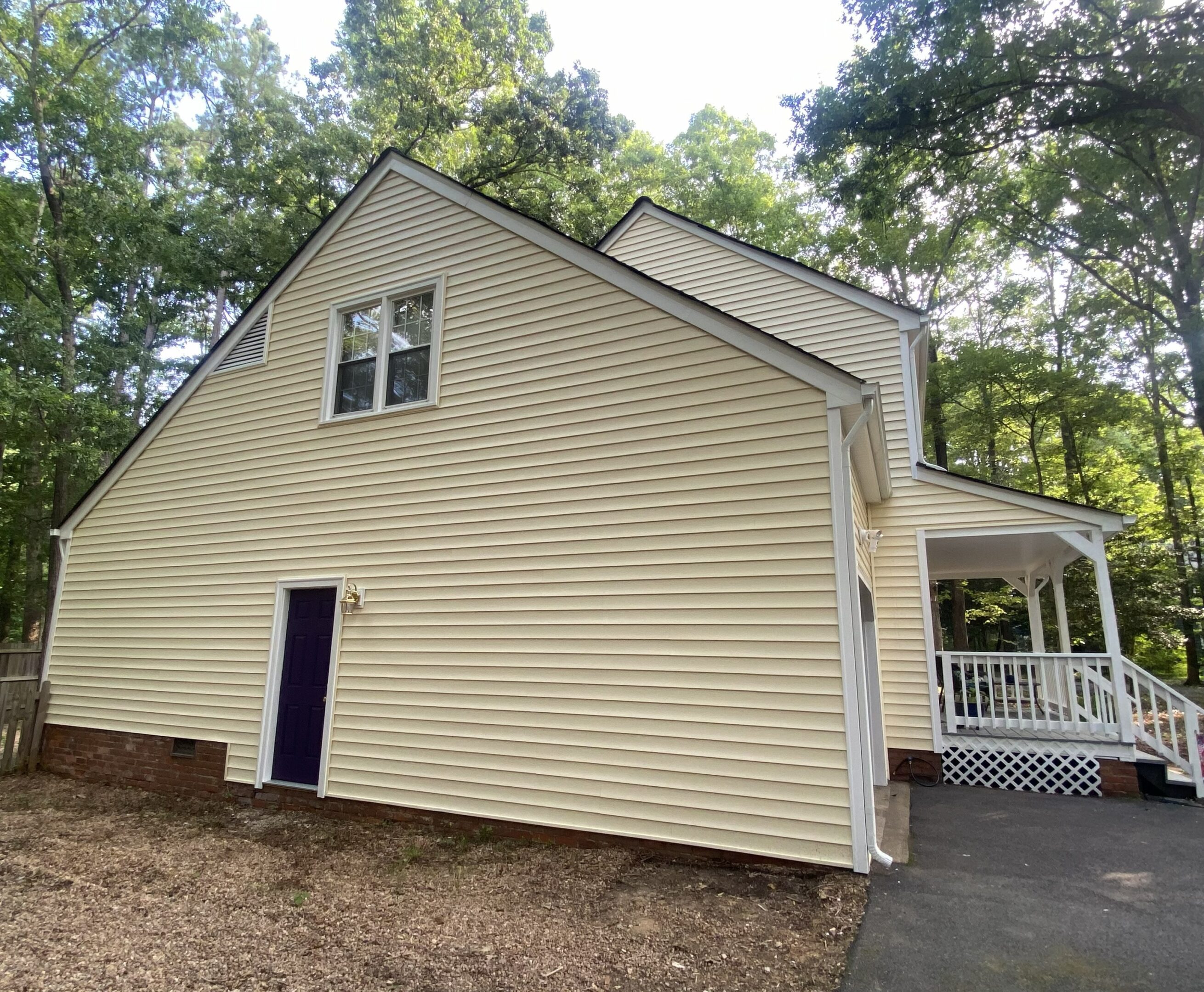 Yellow house with porch and trees nearby.