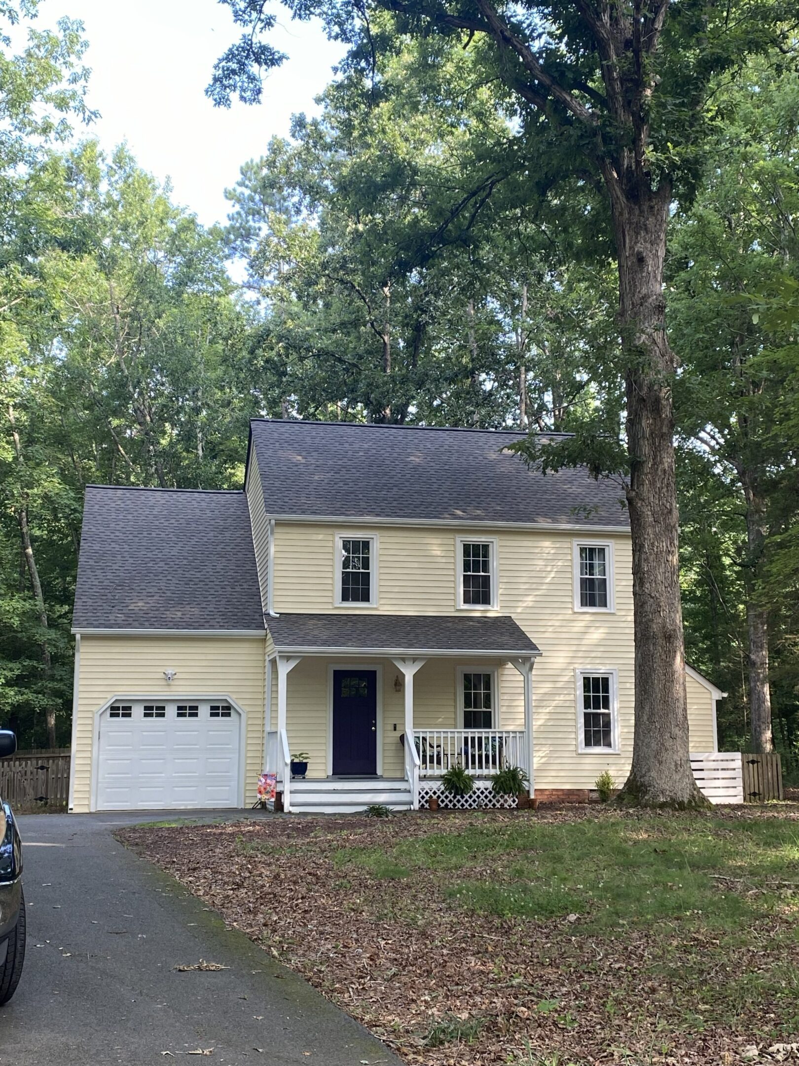 Yellow house with garage, surrounded by trees.