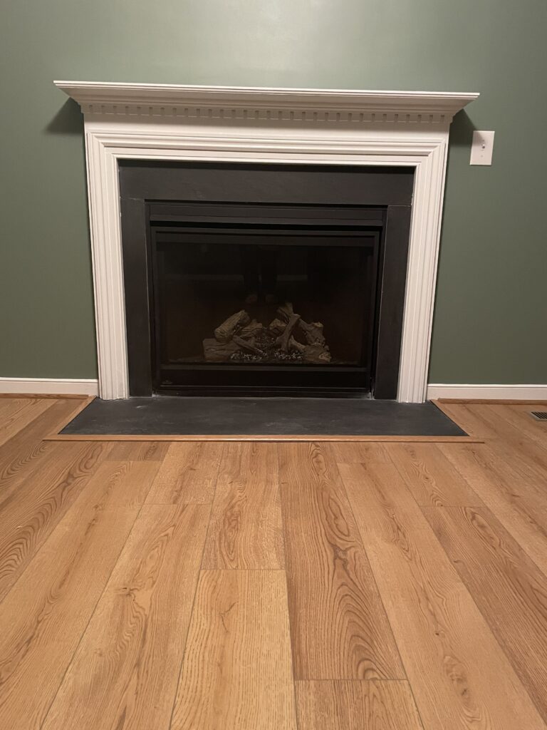 Fireplace with wooden floor and green wall.