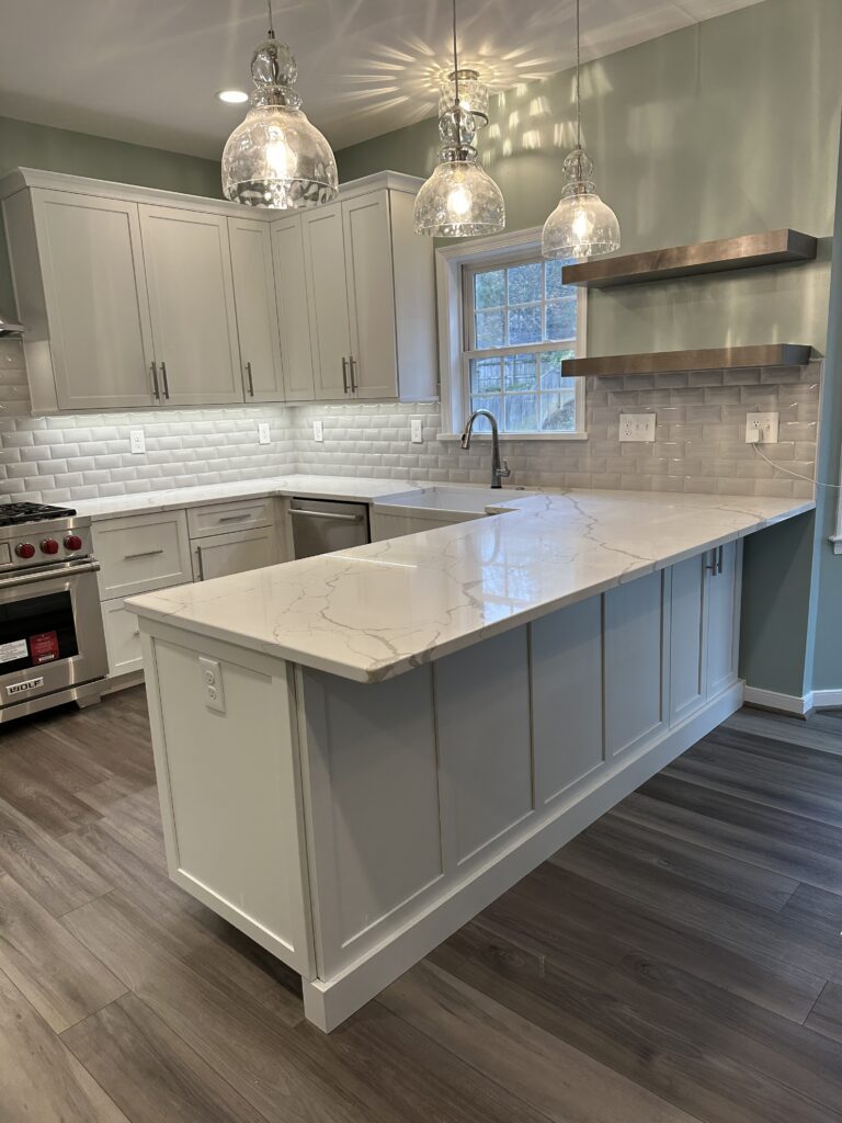 Modern kitchen with marble island and lighting.