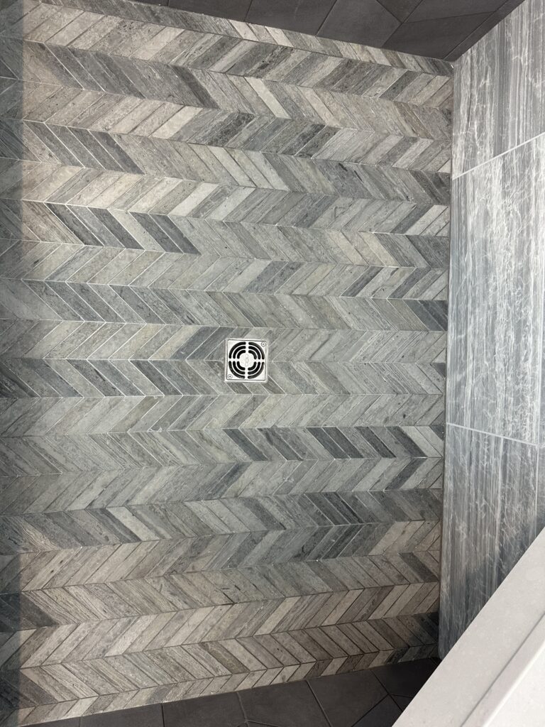 Gray herringbone tile shower floor and wall.