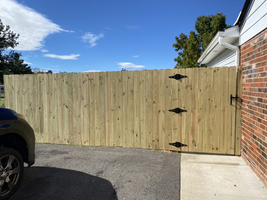 Wooden fence gate beside brick building.