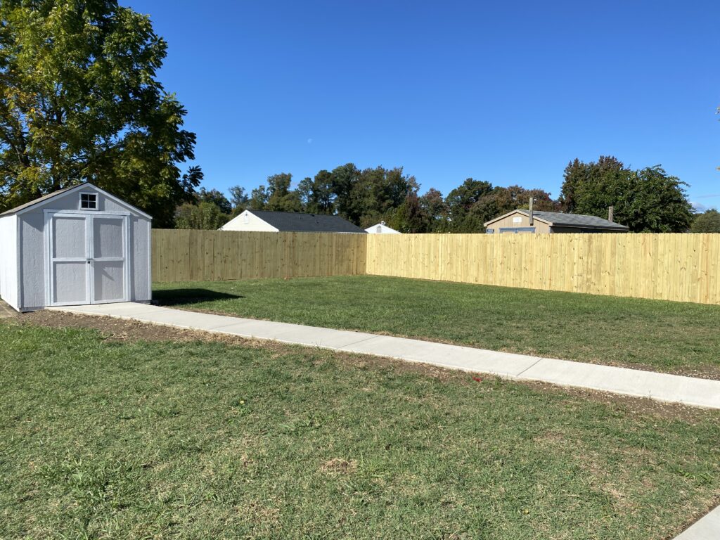 Backyard with shed and wooden fence.