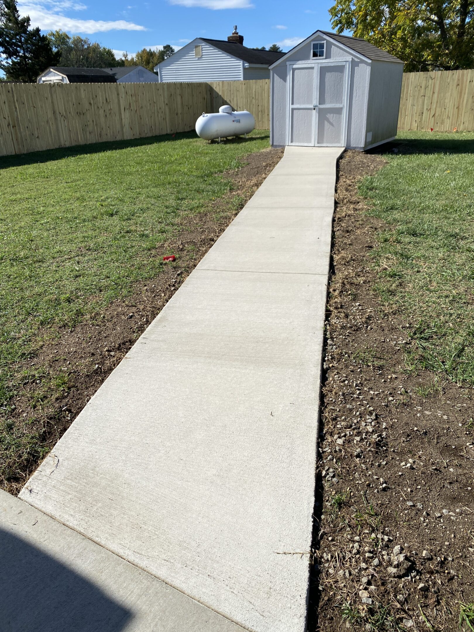 Concrete path leading to small backyard shed.