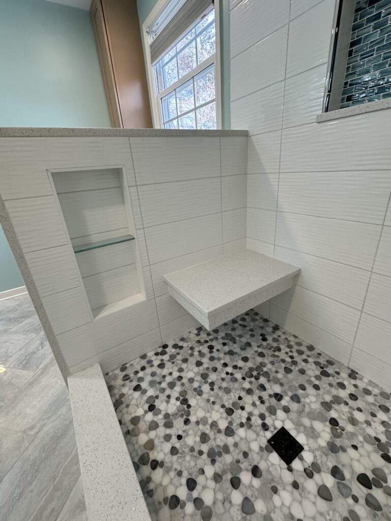 Modern shower with pebble floor and shelf.