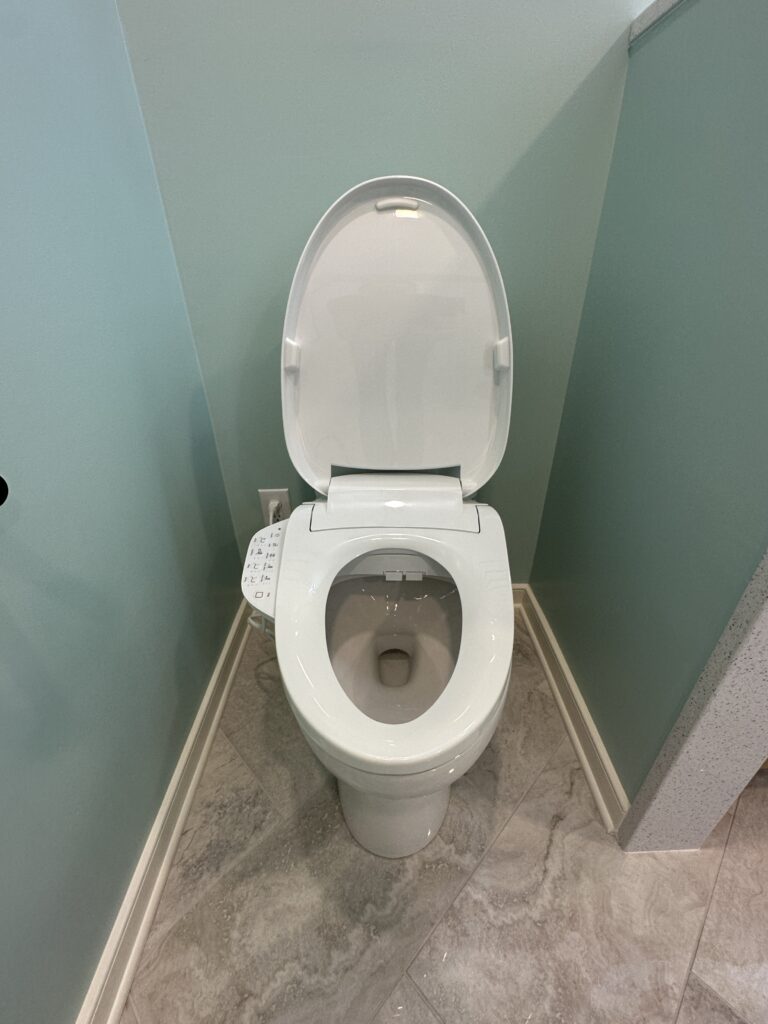 White toilet with open lid against wall.